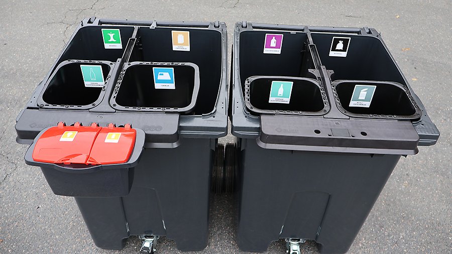 Två avfallskärl med fyra fack i varje, för att lägga olika sortetrs avfall i. Facken är uppmärkta med symboler. 