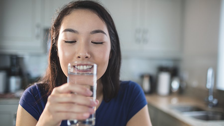 En ung kvinna dricker vatten ur ett glas. 