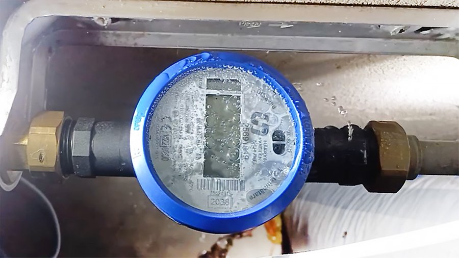 En vattenmätare som blivit frysskadad. Det sprutar vatten från den och under mätarglaset syns frost. 